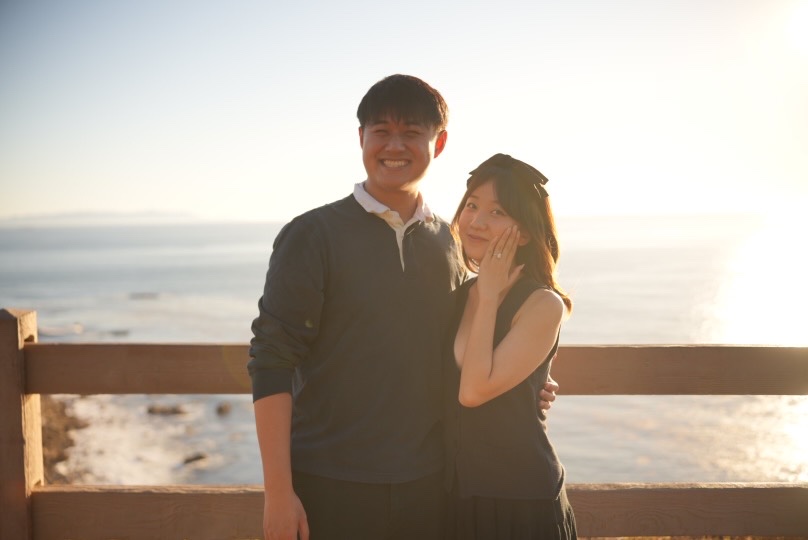 Claire showing her engagement ring with Paul smiling at sunset